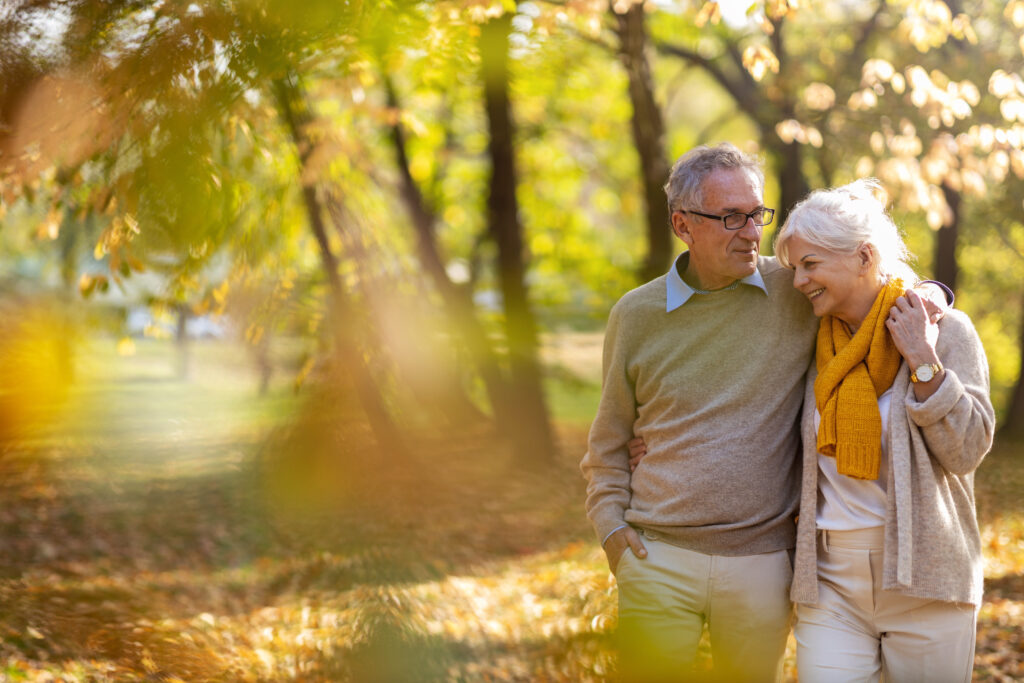 Couple Walking Through Trees in Fall Active Senior Living Communities True Connection Communities